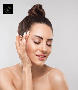 A woman gently touching her face, reflecting the benefits of Kaya's Hydro Boost and Anti-Aging Facial Treatments.