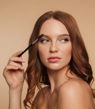 A woman with long hair holds a brush, representing beauty and wellness services at Kaya by Reema Salon.