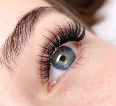 A close-up of a woman's blue eye adorned with long eyelashes, representing beauty and elegance in facial treatments.