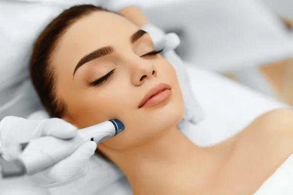 A woman receiving a Hydro Boost facial treatment at Kaya by Reema Salon, utilizing an electric device for anti-aging benefits.