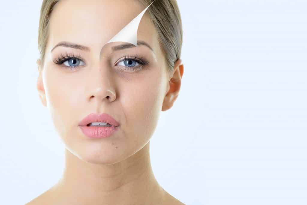 A woman with a white face set against a blue backdrop, showcasing Kaya by Reema Salon's advanced facial treatments.