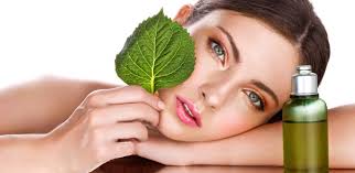 A woman holds a green leaf and a bottle of oil, symbolizing natural beauty and wellness at Kaya by Reema Salon.