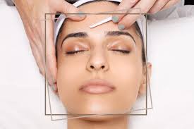 A woman having her eyebrows shaped at Kaya by Reema Salon, highlighting the salon's beauty and facial services.