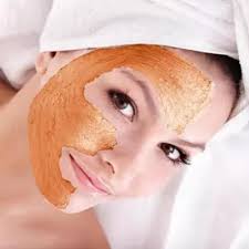 A woman wearing an orange face mask, showcasing Kaya by Reema Salon's facial services and treatments for skin rejuvenation.